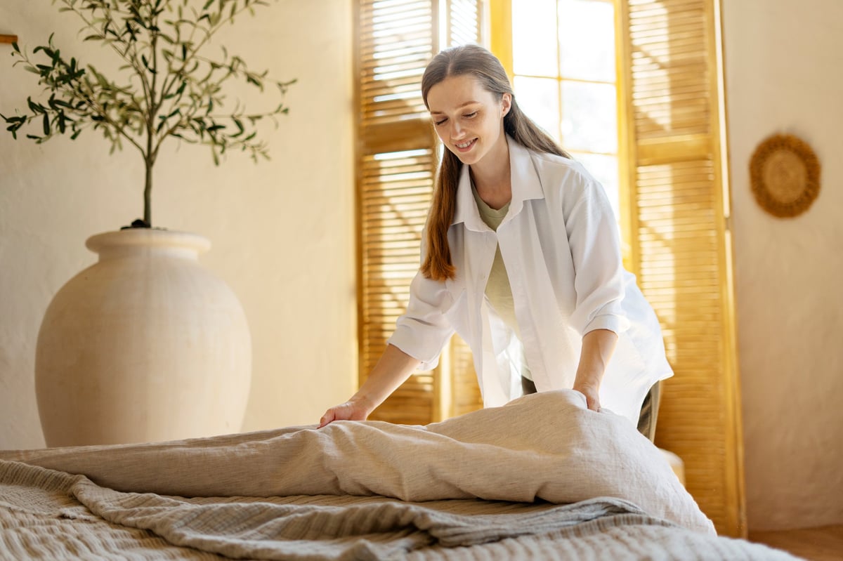 Professional housekeeper making a bed with fresh linen