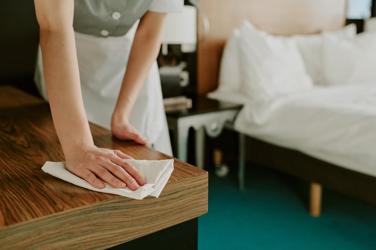 Female hand dusting a wooden table in a clean vacation rental