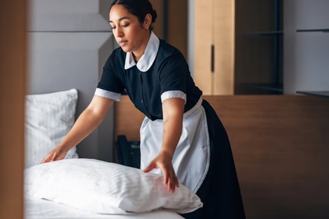 Professional housekeeper making a bed with fresh linen